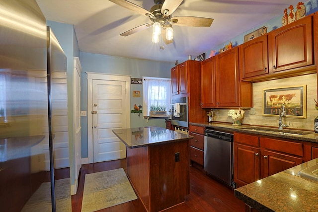 kitchen with dishwasher, sink, a kitchen island, dark stone countertops, and backsplash