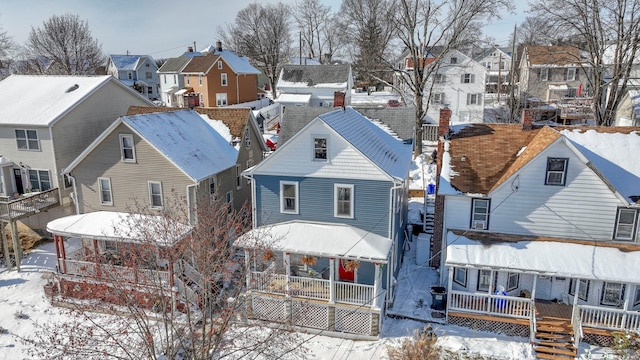 snow covered back of property featuring covered porch