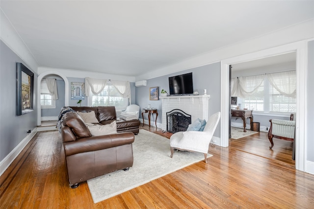 living room with a fireplace, ornamental molding, and wood-type flooring