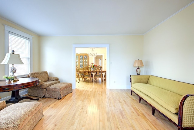 living room featuring a notable chandelier, crown molding, and light hardwood / wood-style flooring