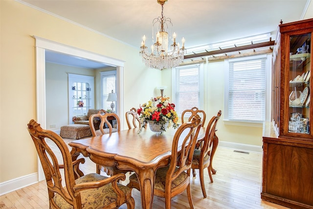 dining area featuring ornamental molding, light hardwood / wood-style floors, a chandelier, and plenty of natural light