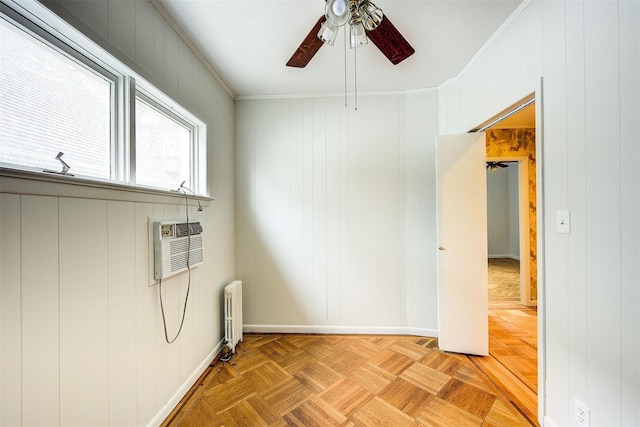 clothes washing area featuring light parquet floors, wood walls, ceiling fan, ornamental molding, and radiator heating unit