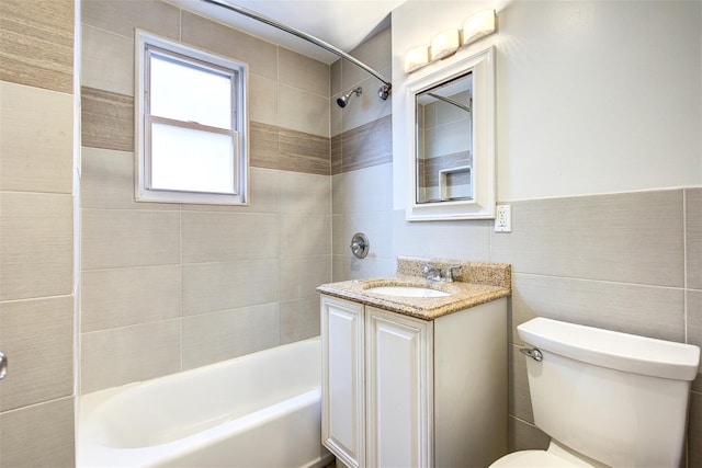 full bathroom with tile walls, toilet, tiled shower / bath, and vanity