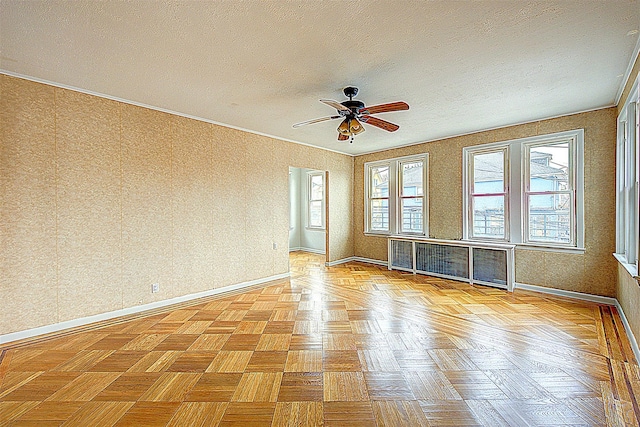 empty room with ceiling fan, crown molding, a textured ceiling, and light parquet floors