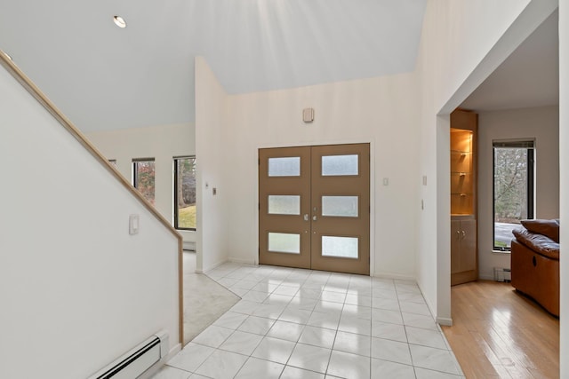 foyer entrance featuring light tile patterned floors, french doors, and a baseboard heating unit