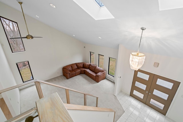 living room featuring ceiling fan with notable chandelier, french doors, lofted ceiling with skylight, and light tile patterned floors