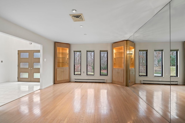 unfurnished living room with french doors, baseboard heating, a notable chandelier, and light hardwood / wood-style flooring