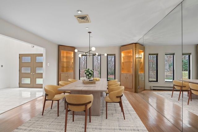 dining room with light hardwood / wood-style floors, french doors, and a chandelier