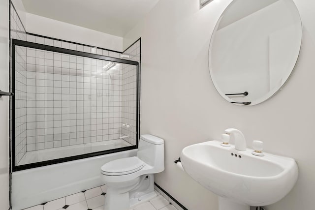 full bathroom featuring toilet, bath / shower combo with glass door, tile patterned flooring, and sink