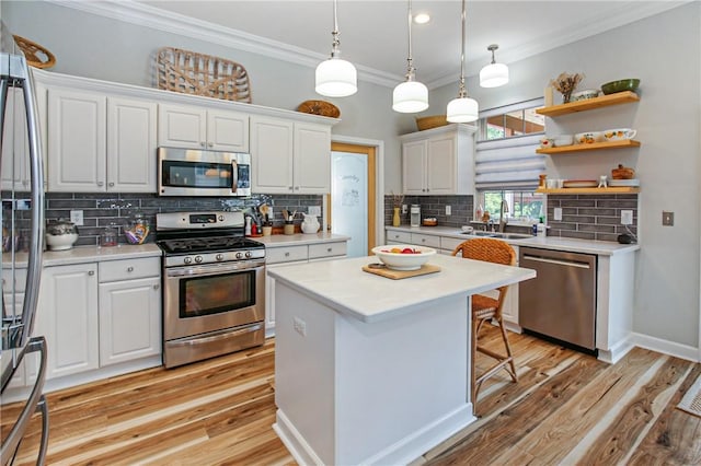 kitchen featuring appliances with stainless steel finishes, sink, white cabinetry, decorative light fixtures, and backsplash