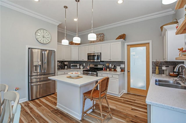 kitchen featuring stainless steel appliances, a kitchen island, backsplash, white cabinetry, and sink