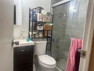 bathroom featuring an enclosed shower, vanity, and toilet