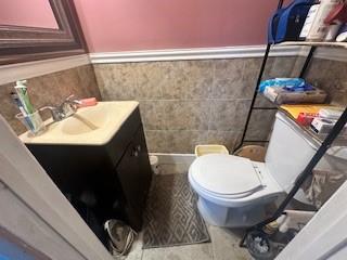 bathroom with vanity, tile walls, and toilet