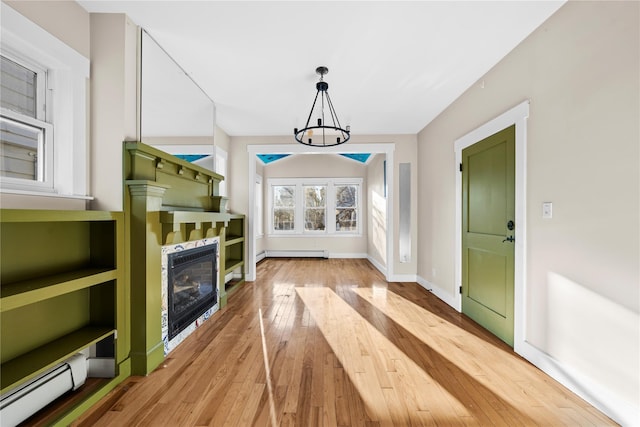 living room with a baseboard heating unit, a notable chandelier, and light hardwood / wood-style floors