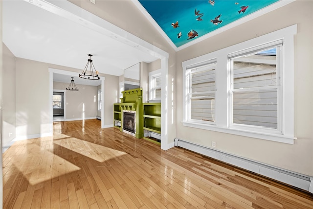 unfurnished living room with a chandelier, hardwood / wood-style floors, lofted ceiling, a baseboard heating unit, and a fireplace