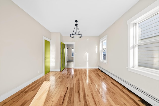 unfurnished dining area featuring a baseboard heating unit, an inviting chandelier, and light hardwood / wood-style floors