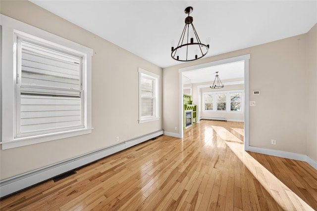 unfurnished dining area featuring light hardwood / wood-style flooring, an inviting chandelier, and a baseboard radiator