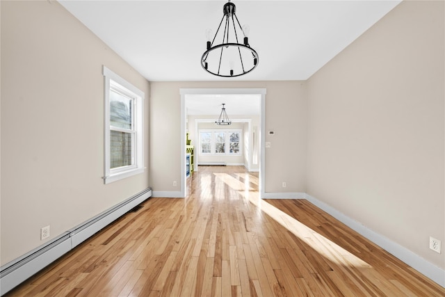 hall with baseboard heating, light wood-type flooring, and an inviting chandelier