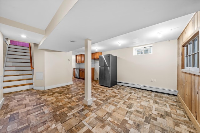 basement with a baseboard radiator and stainless steel refrigerator