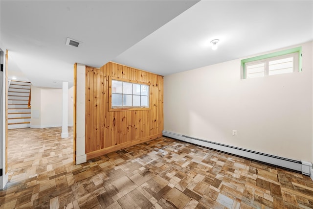 spare room featuring a baseboard heating unit and wood walls