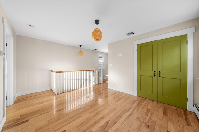 empty room with baseboard heating and light hardwood / wood-style floors