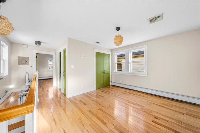 unfurnished room with a healthy amount of sunlight, light hardwood / wood-style flooring, and a baseboard heating unit