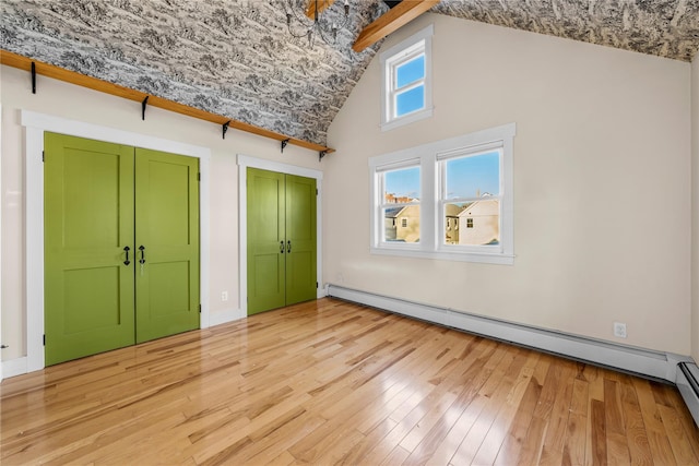 unfurnished bedroom featuring high vaulted ceiling, two closets, baseboard heating, and light hardwood / wood-style floors