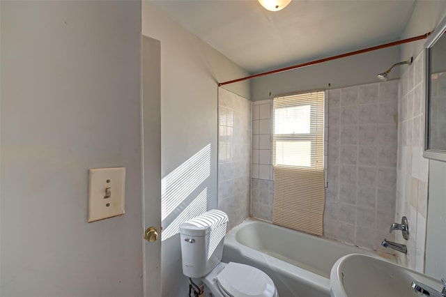 bathroom with tiled shower / bath combo and toilet