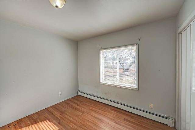 unfurnished room with a baseboard radiator and light hardwood / wood-style flooring