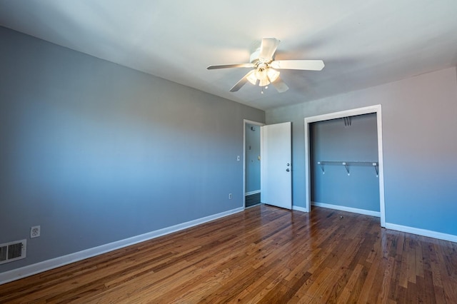 unfurnished bedroom with dark hardwood / wood-style flooring, a closet, and ceiling fan