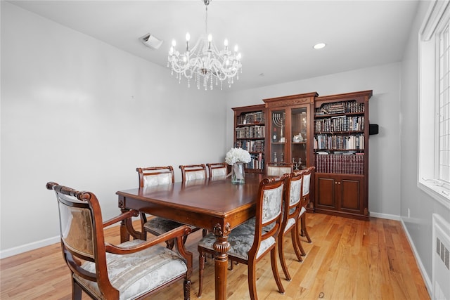 dining space featuring radiator heating unit, light hardwood / wood-style flooring, and a notable chandelier