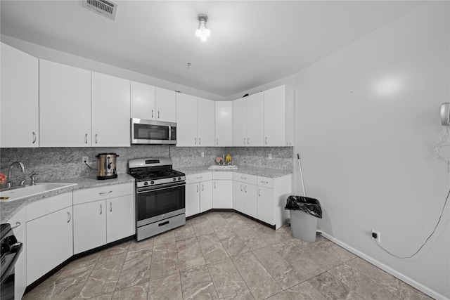 kitchen featuring sink, stainless steel appliances, white cabinets, and decorative backsplash