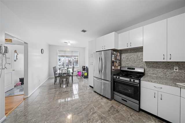 kitchen featuring white cabinetry, decorative backsplash, light stone countertops, and stainless steel appliances