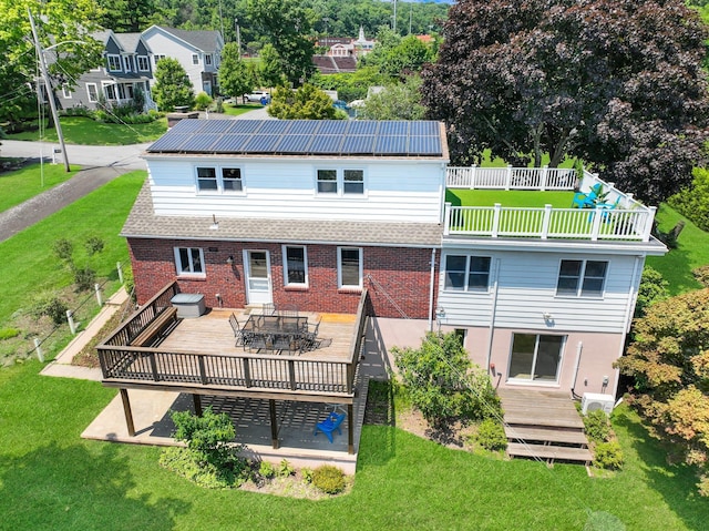 rear view of house with a yard, solar panels, and a wooden deck