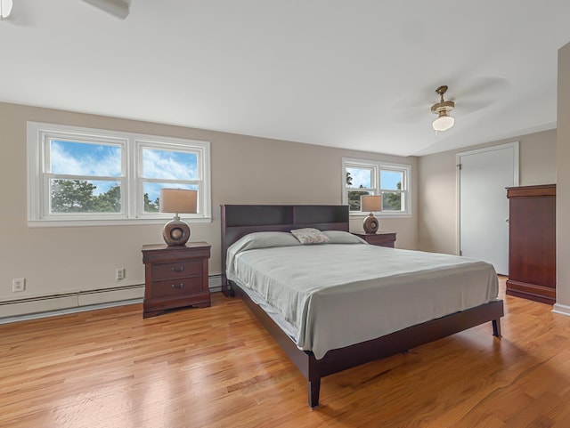 bedroom featuring ceiling fan, baseboard heating, and light wood-type flooring