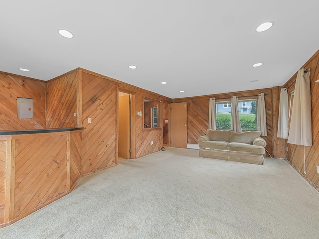 unfurnished living room featuring wooden walls and light carpet