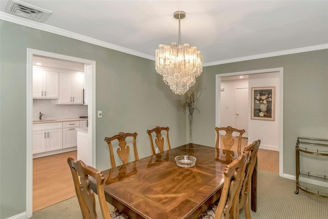 carpeted dining space with sink, ornamental molding, and a notable chandelier