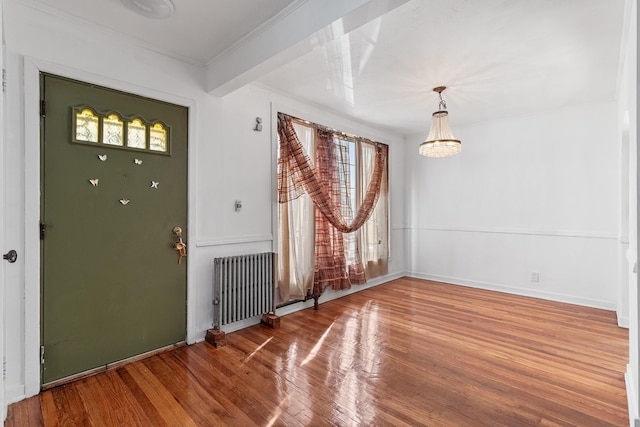 foyer entrance with wood-type flooring, an inviting chandelier, a wealth of natural light, and radiator