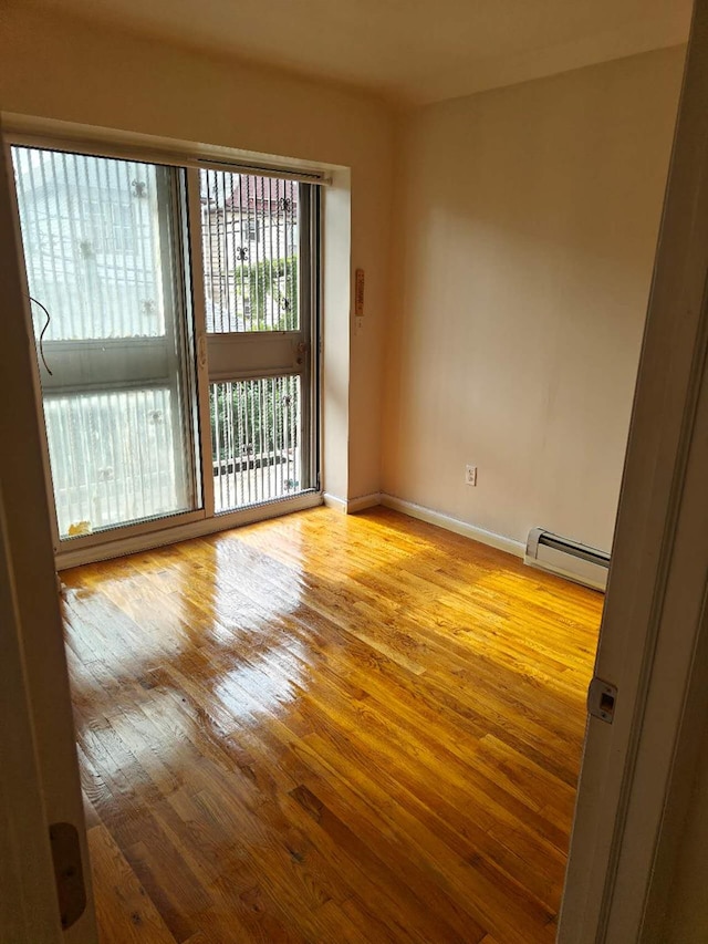 41-38 66th St Unit 2B, Woodside, NY 11377 - spare room featuring baseboard heating, hardwood / wood-style floors, and baseboards