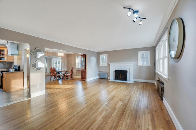 unfurnished living room featuring ornamental molding, radiator heating unit, and light hardwood / wood-style floors