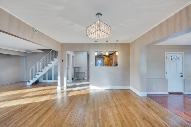 unfurnished living room featuring ornamental molding, a chandelier, and hardwood / wood-style floors