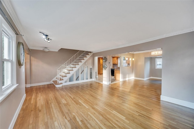 unfurnished living room with crown molding, rail lighting, hardwood / wood-style floors, and a notable chandelier