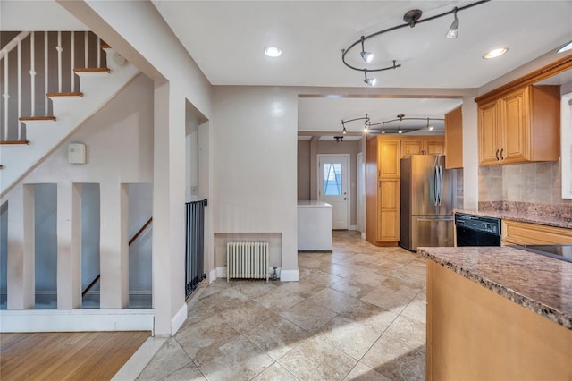 kitchen with light stone counters, stainless steel refrigerator, black dishwasher, radiator, and backsplash