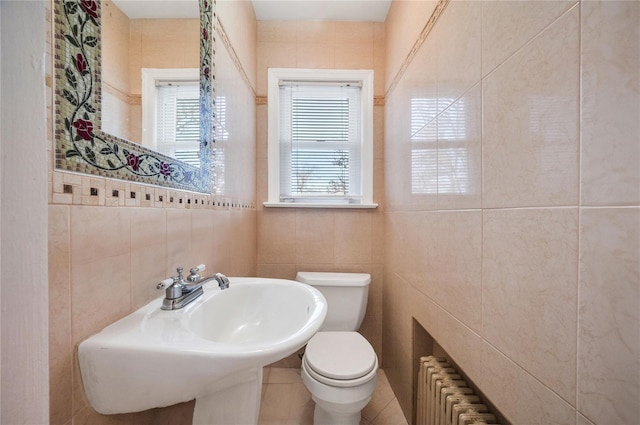 bathroom with tile walls, radiator heating unit, and toilet