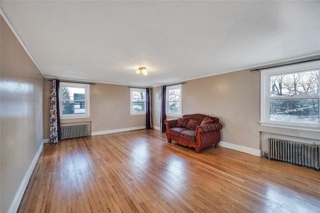 living area featuring crown molding, radiator, and light wood-type flooring