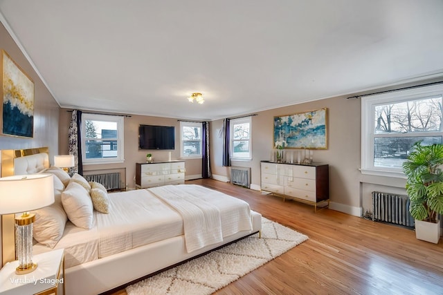 bedroom with multiple windows, radiator, and light wood-type flooring