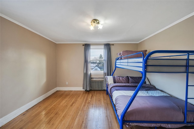 bedroom with radiator heating unit, crown molding, and light hardwood / wood-style flooring