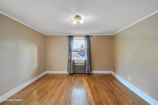 empty room featuring crown molding, radiator heating unit, and light wood-type flooring