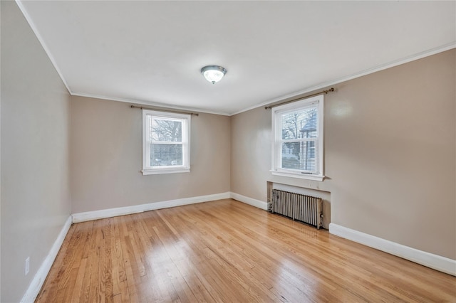 empty room featuring crown molding, radiator heating unit, and light wood-type flooring