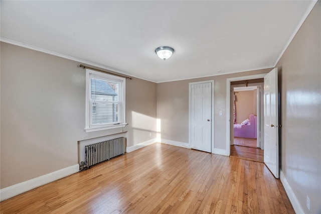 unfurnished bedroom with ornamental molding, radiator heating unit, and light hardwood / wood-style flooring